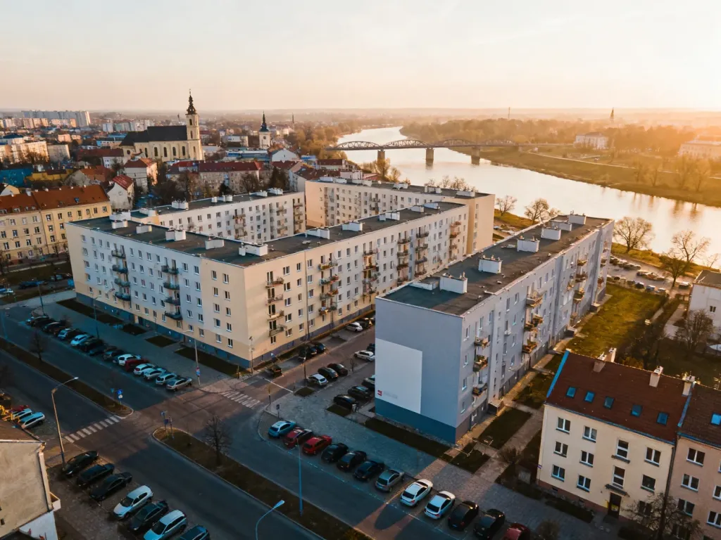 Panorama centrum Opola z nowymi blokami mieszkalnymi, ukazująca zabudowę i otoczenie miasta o zachodzie słońca, no text on the picture